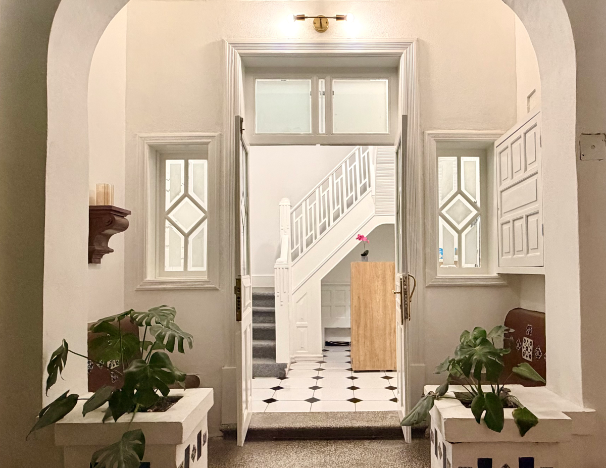 Bright wax studio hallway with white walls, modern globe lighting, and view of green foliage.