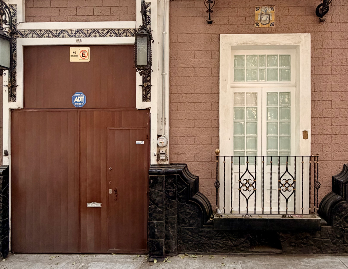 Wax studio storefront with brown door, security signage, and white window with balcony.